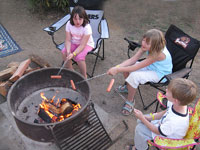 My kids roasting hotdogs around the campfire
